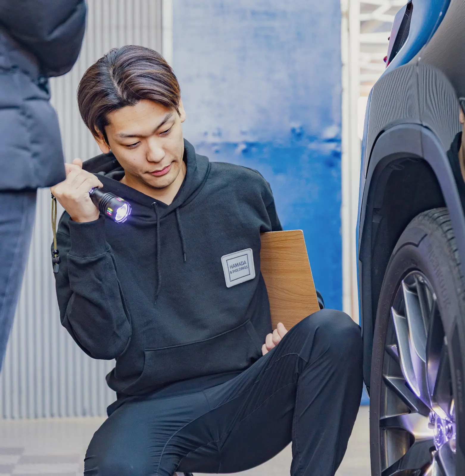 車のタイヤにライトを当てて査定をしている男性の写真